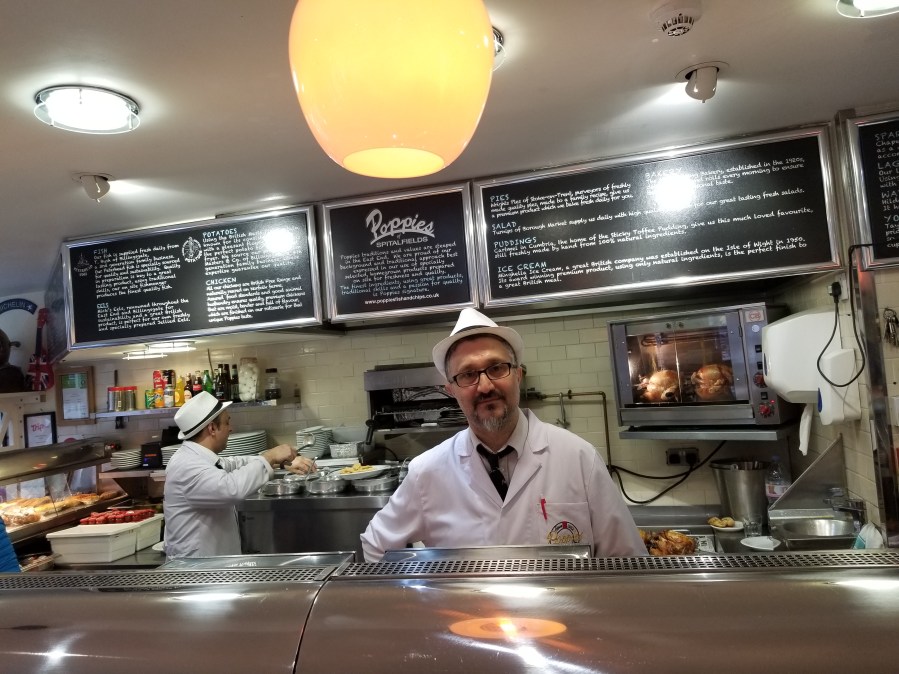 Counter service worker at Poppies, London, lauded as serving the city's best fish and chips. Photo by Anastasia Mills Healy, taken on an Eating Europe food walking tour.